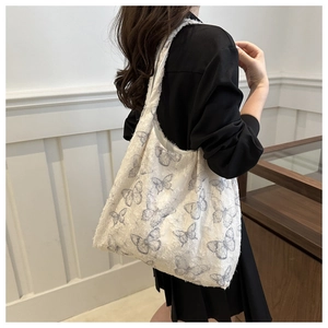 Detailed shot of white tote bag with butterfly patterns on a model in a cozy interior