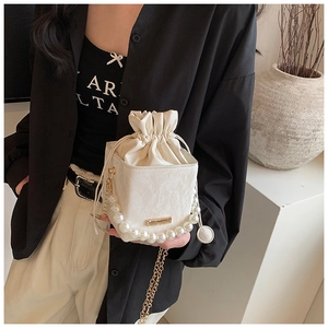 Detail of cream PU leather bucket bag with pearl handle and golden chain strap