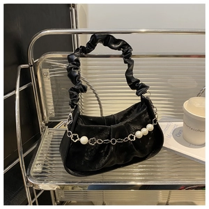 Detail of black pleated crossbody bag featuring elegant pearl and metal floral chain
