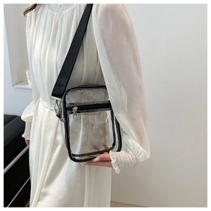 Close-up of a clear PVC crossbody bag with a wide black strap on a white dress