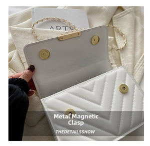 Makro-Detail des goldenen Magnetverschlusses an einer weißen gesteppten Klapptasche