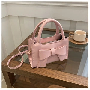 Detail of pink fashion handbag featuring a large bow and premium metal zipper closure