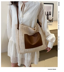 Straw woven tote bag with brown leather pocket detail shown in a cozy lifestyle setting
