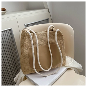 Detail of beige straw tote bag featuring V-shaped weave pattern and brown leather pocket