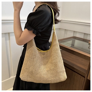 Detail of woven straw tote bag with yellow leather strap on model's shoulder