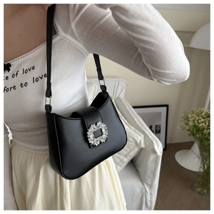 Detailed view of a black leather underarm bag with a sparkling crystal round buckle