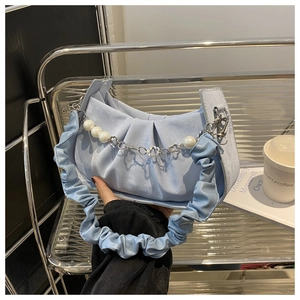 Close-up of light blue pleated handbag featuring a pearl and floral metal chain