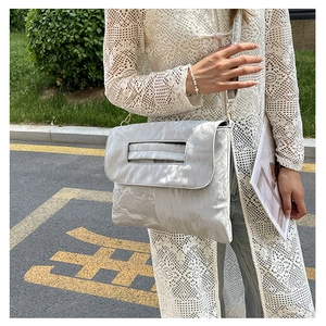Detail of silver metallic wrinkled texture and rectangular cutout handle on crossbody bag