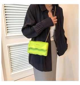 Detail of neon green chain bag with wavy flap edge and gold lettering on shoulder