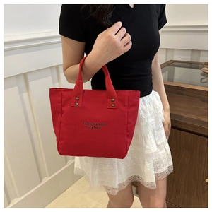 Close-up of red canvas tote bag with black lettering and durable metal rivets