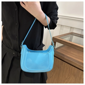 Detail of bright blue patent leather crescent bag with U-shaped stitching and adjustable strap