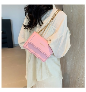 Detail of pink shoulder bag with wavy flap edge and elegant gold chain strap