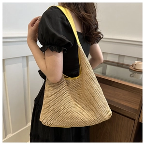 Detail of straw woven tote bag featuring yellow leather straps and hollow weave texture