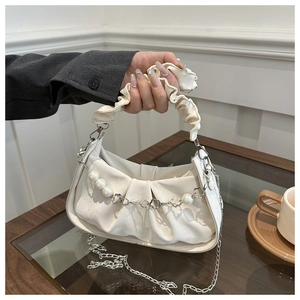 Close-up of white ruched bag featuring pearl chain and flower metal strap detail