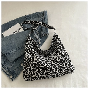 Flat lay of a leopard print nylon tote bag with a denim jacket and lifestyle props