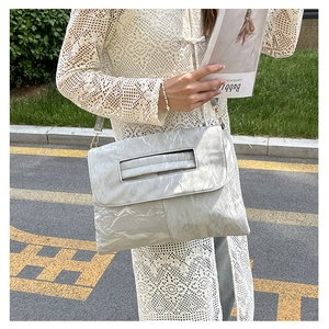Silver wrinkled tote bag with cutout handle and gold hardware on street background