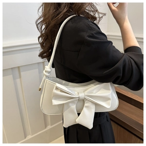 Detail of white PU leather shoulder bag featuring a large bow and gold metal buckle