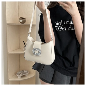 Detail of elegant off-white shoulder bag featuring a sparkling crystal square buckle