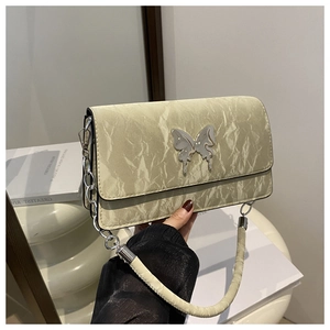 Detail of cream pleated crossbody bag featuring a silver metal butterfly buckle and chain
