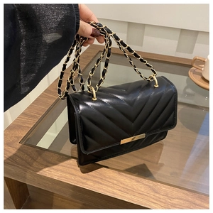 Detail der schwarzen V-gesteppten Ledertasche mit Goldschnalle und Kettenriemen