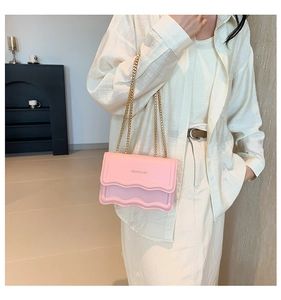 Detailed view of pink chain crossbody bag with wavy edge and golden brand logo
