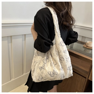 Detail of soft plush fabric tote bag with blue butterfly patterns in a casual setting