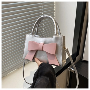 Detail view of silver metallic leather handbag with a large decorative pink bow detail