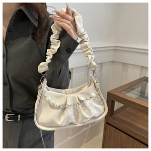 Close-up of ruched cream cloud bag featuring pearl and heart charm chain detail