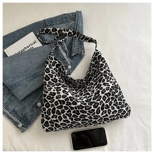 Detailed top view of large leopard print nylon tote bag with casual lifestyle props