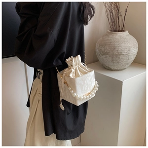 Detail of white marble textured box bag with pearl handle and satin inner pouch