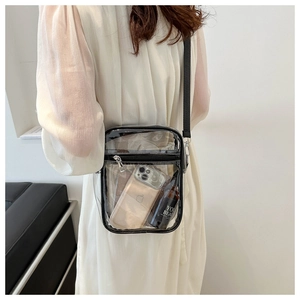 Side view of a clear PVC crossbody bag with black trim worn by a model on plain background