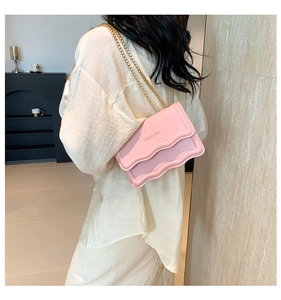Detail of pink vintage shoulder bag with wavy flap design and gold chain strap