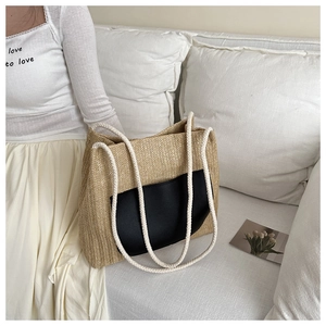 Detail of woven straw tote bag featuring black contrast pocket and white cotton rope handles