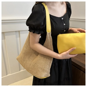 Detail of woven straw tote bag with yellow leather straps and matching zip pouch