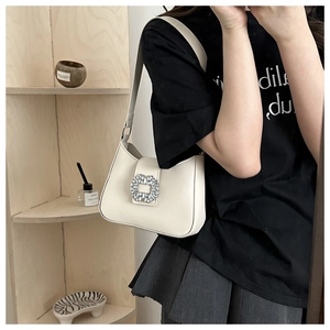 Detail of elegant cream shoulder bag with luxury sparkling crystal square buckle