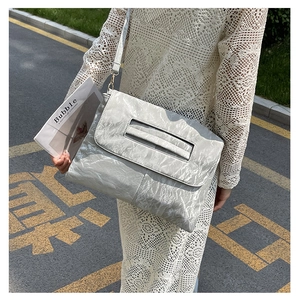 Detail of light grey pleated texture crossbody bag with adjustable shoulder strap