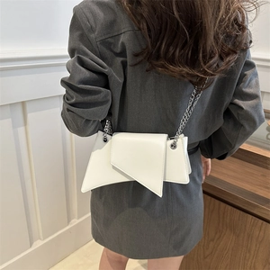 Sac à bandoulière minimaliste en cuir blanc avec chaîne argentée porté par un modèle