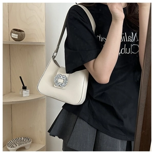 Detail of off-white PU leather hobo bag with a large crystal buckle shown on a model