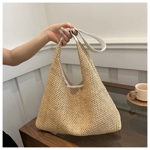 Close-up of hand-woven straw tote bag with white leather handle and natural texture