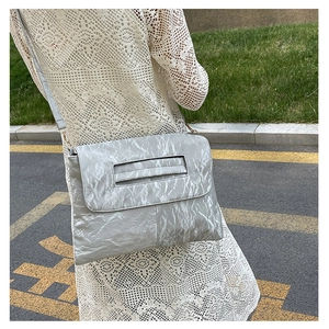 Détail du sac à bandoulière plissé gris clair avec texture et poignée intégrée