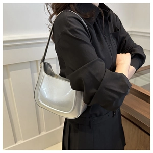 Chic silver metallic shoulder bag worn by model showing its sleek half-moon design