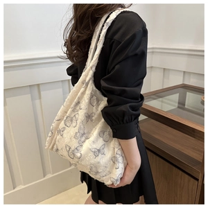 Detail of white canvas shoulder bag featuring blue butterfly prints and frayed fabric texture