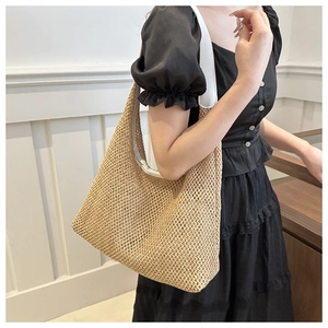 Detailed close-up of large straw tote bag with white leather straps and woven texture