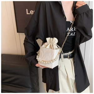 Détail du sac boîte crème avec poignée en perles, cordon de serrage et chaîne dorée