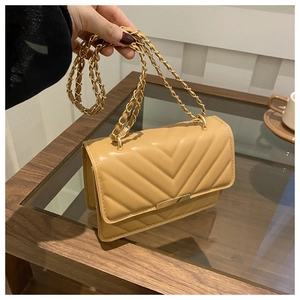 Detail der khakifarbenen Stepptasche mit goldener Kette und edlem Metallbesatz