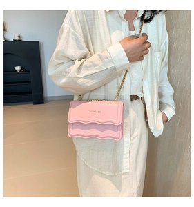 Detail of light pink crossbody bag with wavy pleated texture and gold chain strap