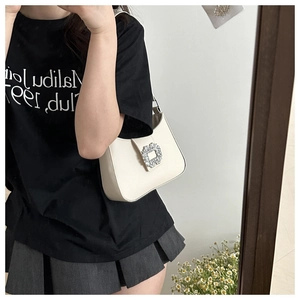 Detail of white hobo bag featuring a large sparkling crystal buckle on premium leather