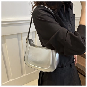 Detail of a silver metallic shoulder bag showing its glossy finish and curved shape