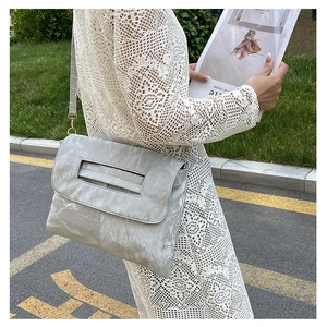 Détail du sac à bandoulière argenté à texture plissée et fine lanière en extérieur