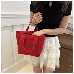 Détail d'un sac à main en toile rouge avec logo textuel dans un cadre domestique